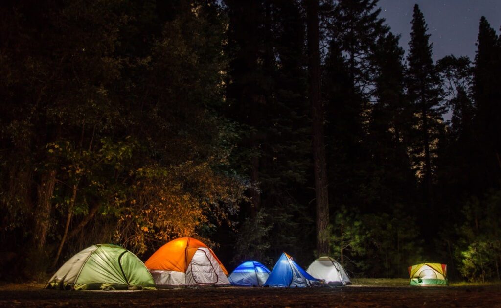 Camping tents illuminated under starry night sky