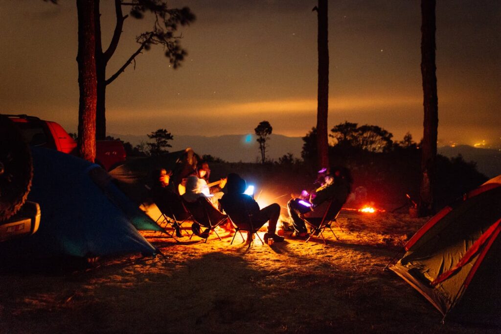 Group of campers sitting near their tent enjoying sunset view